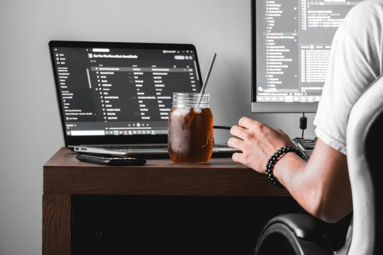 Une personne travaillant sur son bureau, avec un café glacé dans une jarre en verre