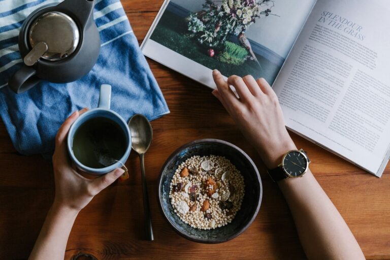 personne tenant une tasse en ceramique bleue et un magazine blanc